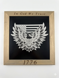 Framed artwork with an eagle design, American flag, and 'In God We Trust' text on a black background.